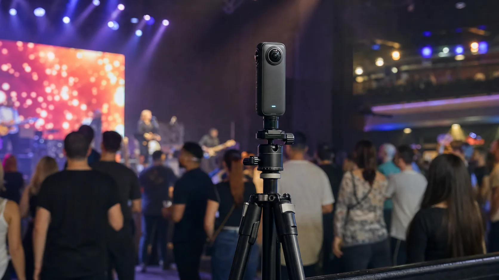 מצלמת Insta360 X5 על חצובה יציבה במוקד אירוע, קהל וקצת תאורת במה מסביב, גובה עיניים